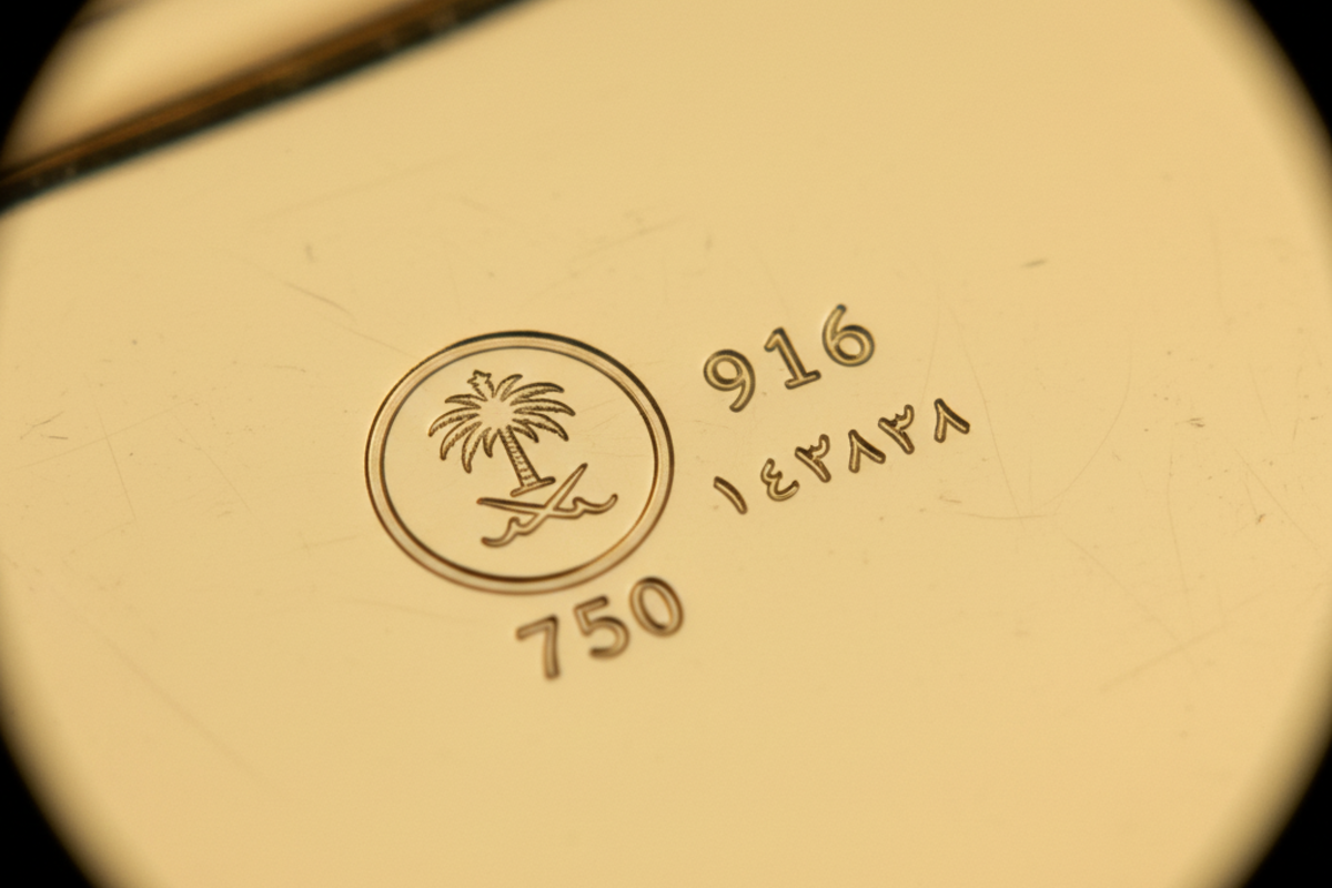 دمغة وختم العيار على قطعة ذهب سعودية توضح رقم العيار 18 قيراط ورمز المصنع للتحقق من الأصالة